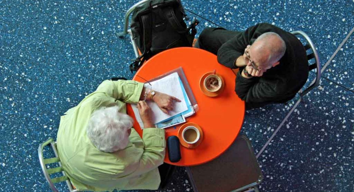 Could you tell me more about that? Two people talking at a small round table