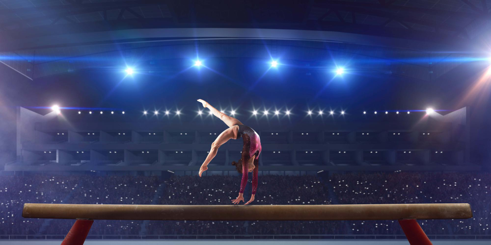 Female gymnast doing a complicated trick on gymnastics balance beam in a professional arena