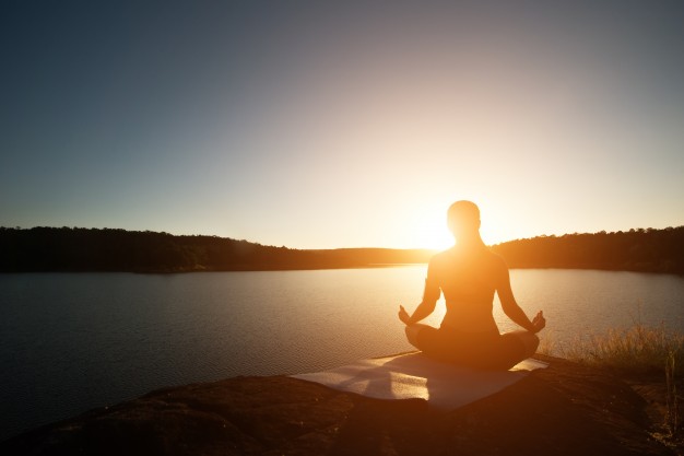 Woman meditating at sunrise or sunset