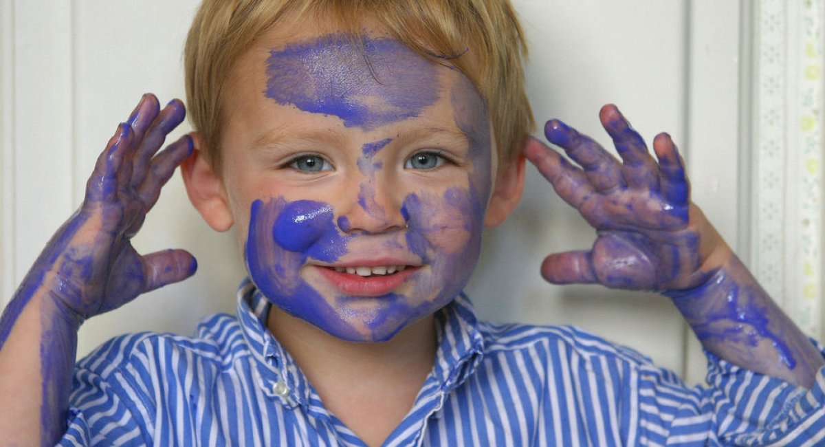 A picture of a little boy with paint on his face.