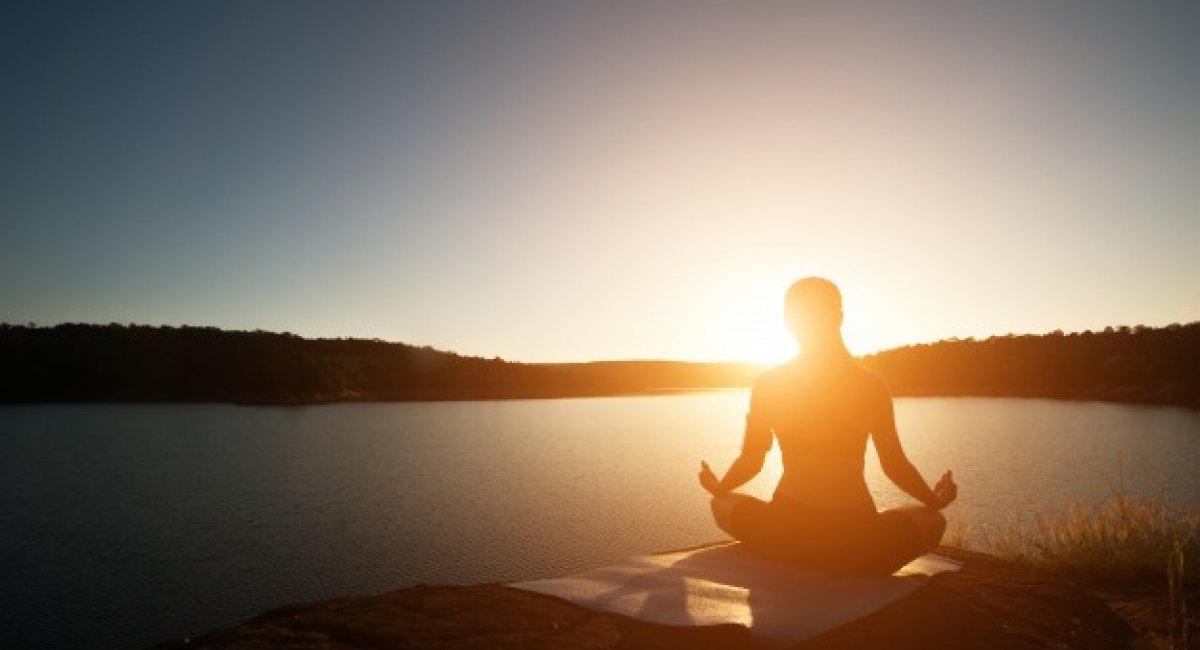 Woman meditating at sunrise or sunset