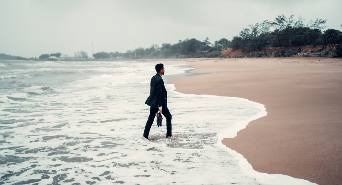 Man in business suit walking on a beach
